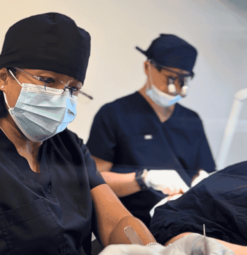 Surgeons in scrubs and masks performing a medical procedure. Healthcare professionals focused on patient care during surgery.